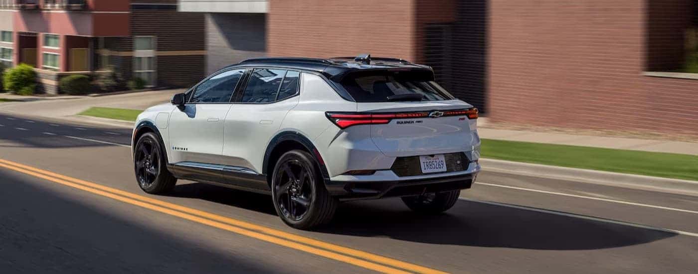 A white 2025 Chevy Equinox EV RS driving in a city.
