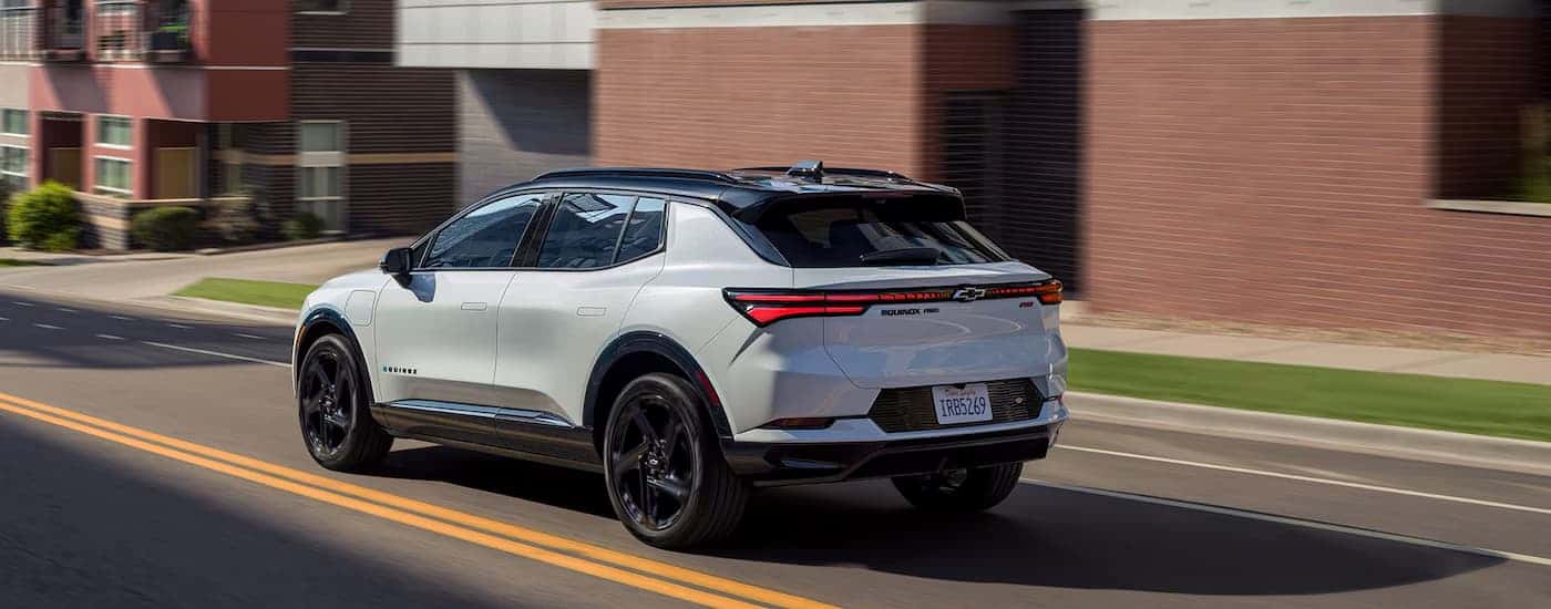 A white 2025 Chevy Equinox EV driving down a city street