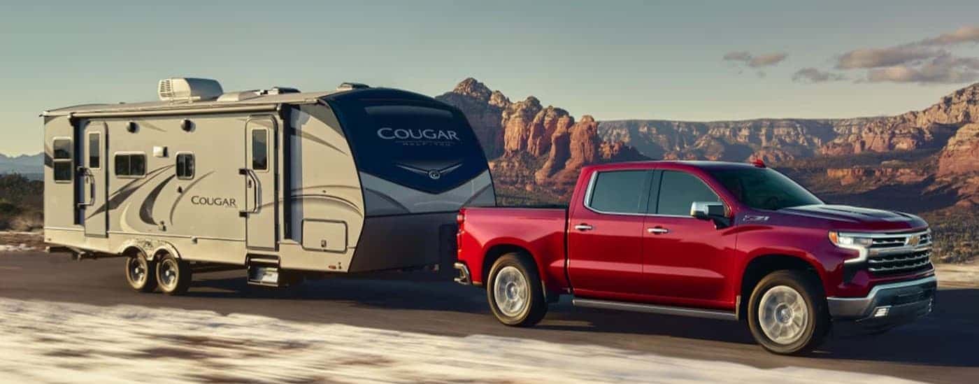A red 2026 Chevy Silverado 1500 for sale near Exeter towing a trailer.
