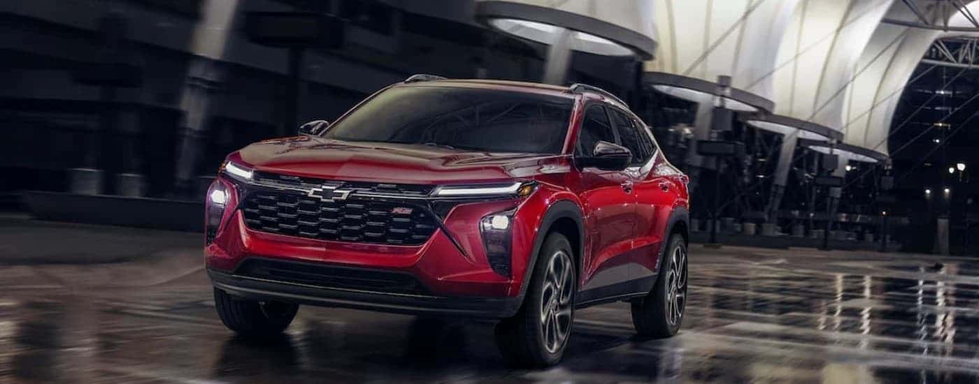 A red 2025 Chevy Trax RS driving in wet conditions.