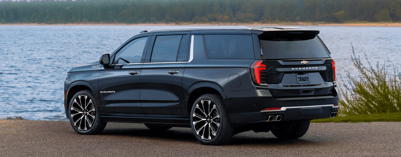 Black 2026 Chevy Suburban parked by a lake from the rear