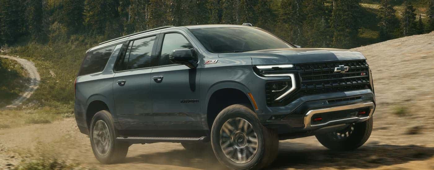 A blue 2026 Chevy Suburban Z71 off-roading on a trail