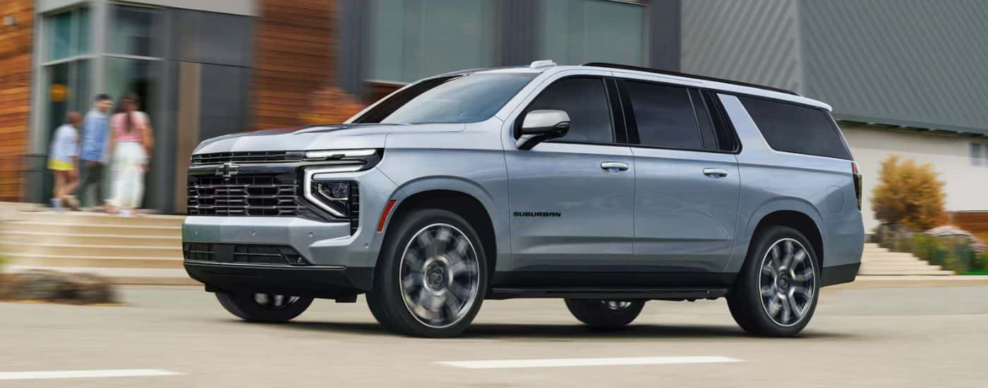 Silver 2026 Chevy Suburban driving past an apartment building