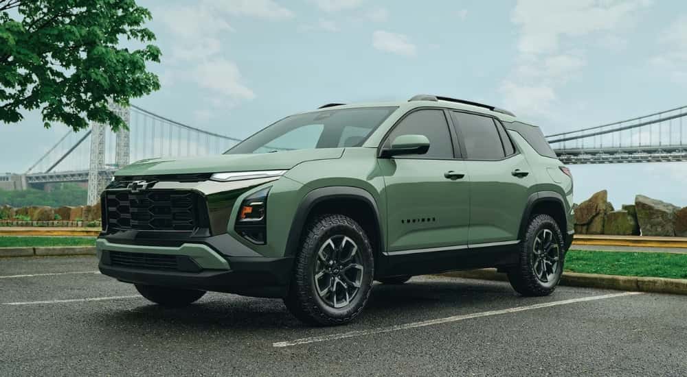 A green 2026 Chevy Equinox ACTIV driving away from a bridge.