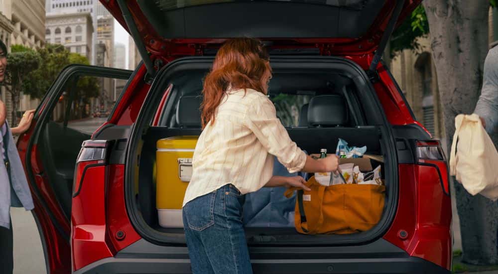People loading groceries into the trunk of a red 2026 Chevy Equinox.