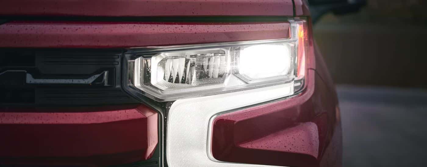 Close up of a headlight on a red 2026 Chevy Silverado 1500 RST.