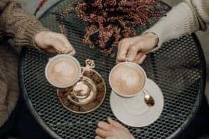 Two people holding cups of coffee at a coffee shop table