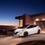 white 2023 nissan leaf parked in the driveway of a house