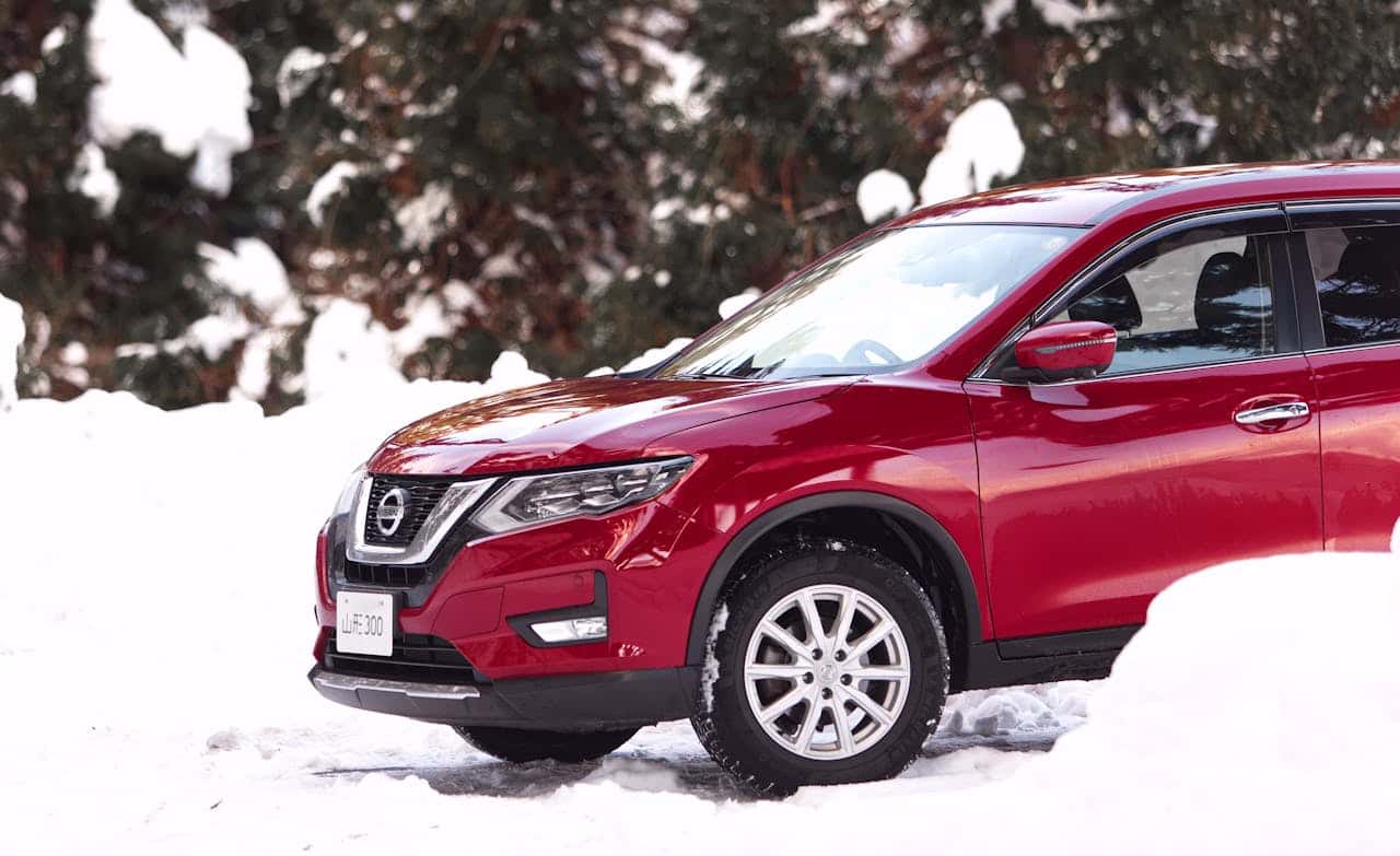 red nissan rogue driving in snow