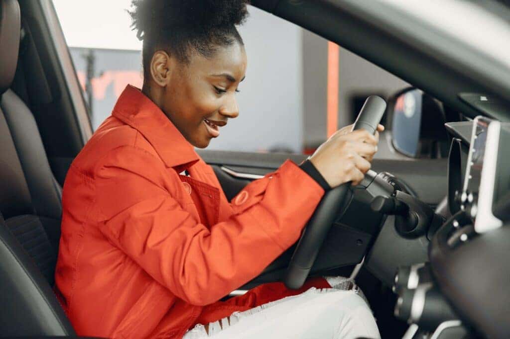 young female teenager holding steering wheel of nissan