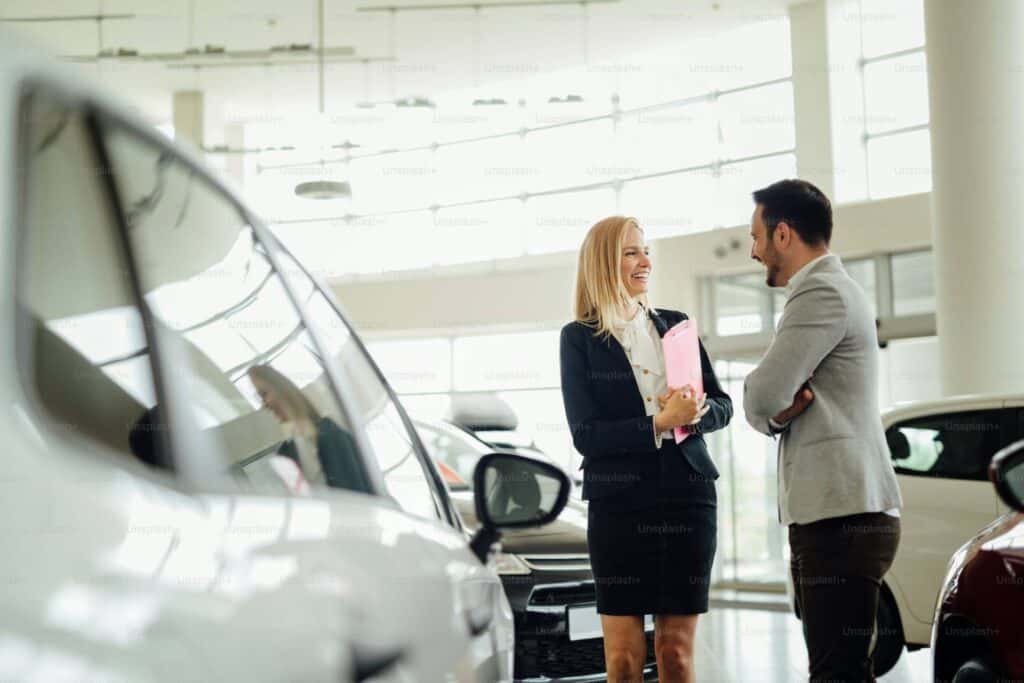 man and woman at car dealership to sell car
