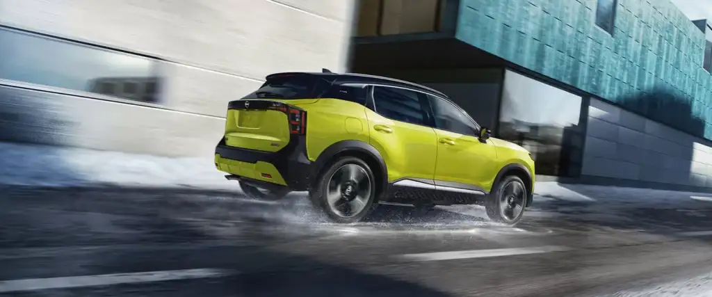 2027 nissan kicks side profile driving down wet city road
