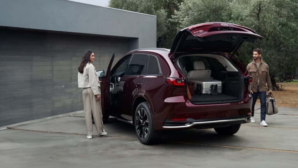 Black 2026 Mazda CX-90 with the back hatch open and two people on the outside.
