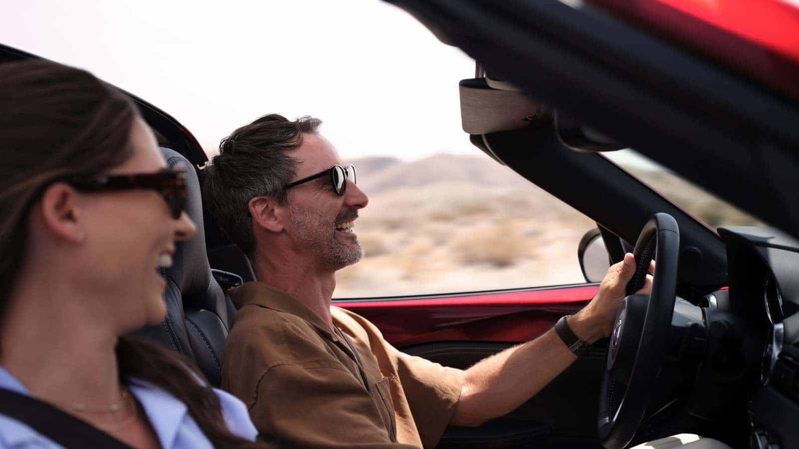 owner of Mazda MX-5 Miata smiling with the hood off as he drives it in Central Valley