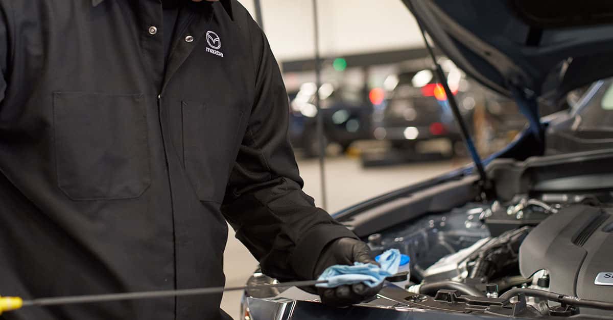Mazda service technician changing vehicle's oil