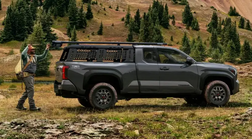 A Toyota Tacoma pickup truck driving through a scenic mountain trail