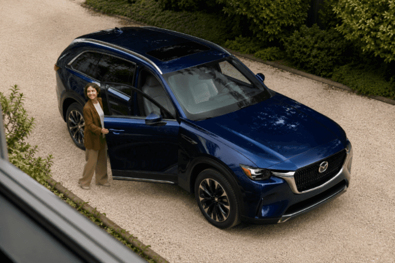 Navy blue Mazda CX-90 SUV on a garden driveway