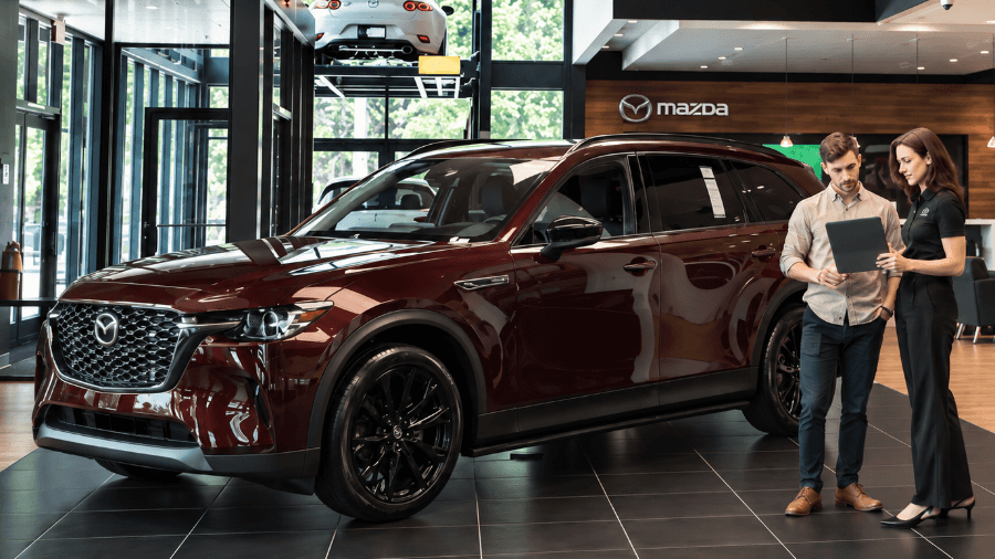 Customer and Mazda specialist beside a burgundy Mazda SUV in a modern Mazda showroom