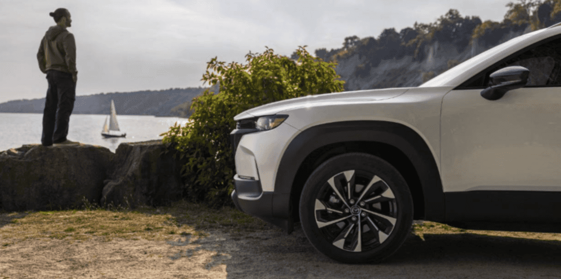 Man admiring a lookout near a hybrid Mazda CX-50 SUV