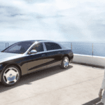 Maybach Luxury Mercedes-Benz Vehicle on a beautiful glass enclosure overlooking the ocean with a woman admiring the car in a cream summer dress.