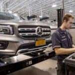Professional technician performing a vehicle inspection on a Mercedes-Benz SUV