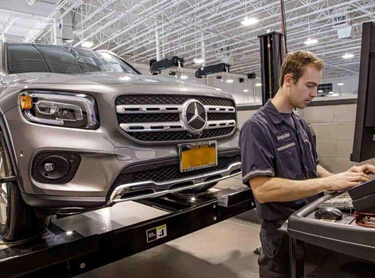 Professional technician performing a vehicle inspection on a Mercedes-Benz SUV