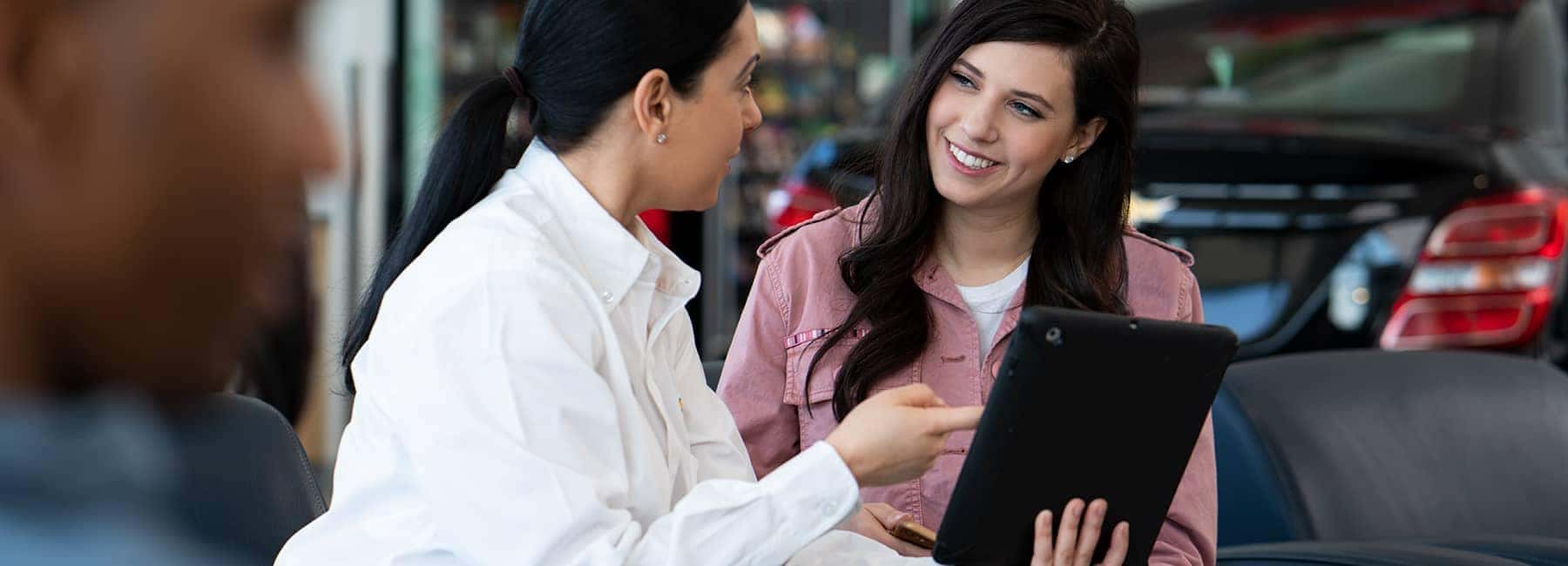 Chevrolet-saleswoman-talking-with-woman-and-pointing-at-clipboard