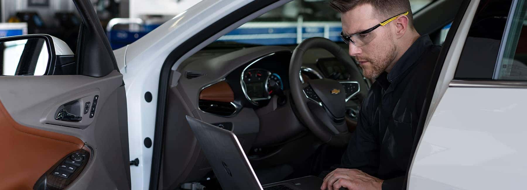 Chevrolet-service-technician-sitting-in-a-car-looking-at-his-laptop