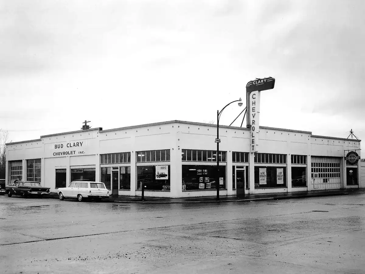 A long white dealership building with big showroom windows, a Bud Clary Chevrolet, Inc. sign and a tall Clary Chevrolet sign on the roof, in a black and white photo