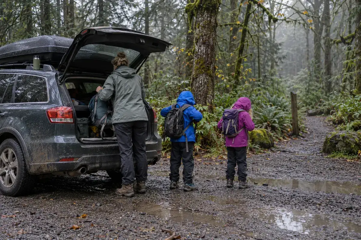 A loaded wagon at a Columbia River Gorge trailhead at dawn while a parent and two kids put on their packs