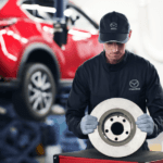 Mazda technician holding brake rotor during service repair