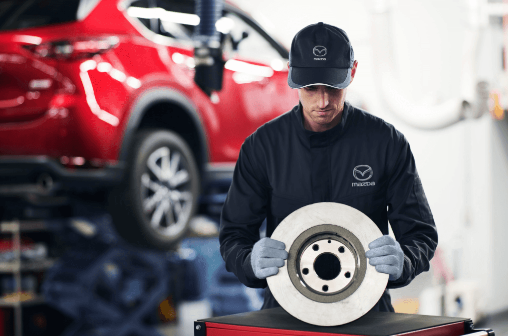 Mazda technician holding brake rotor during service repair