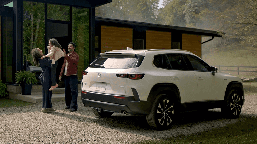 Mazda CX-50 parked outside modern home with family