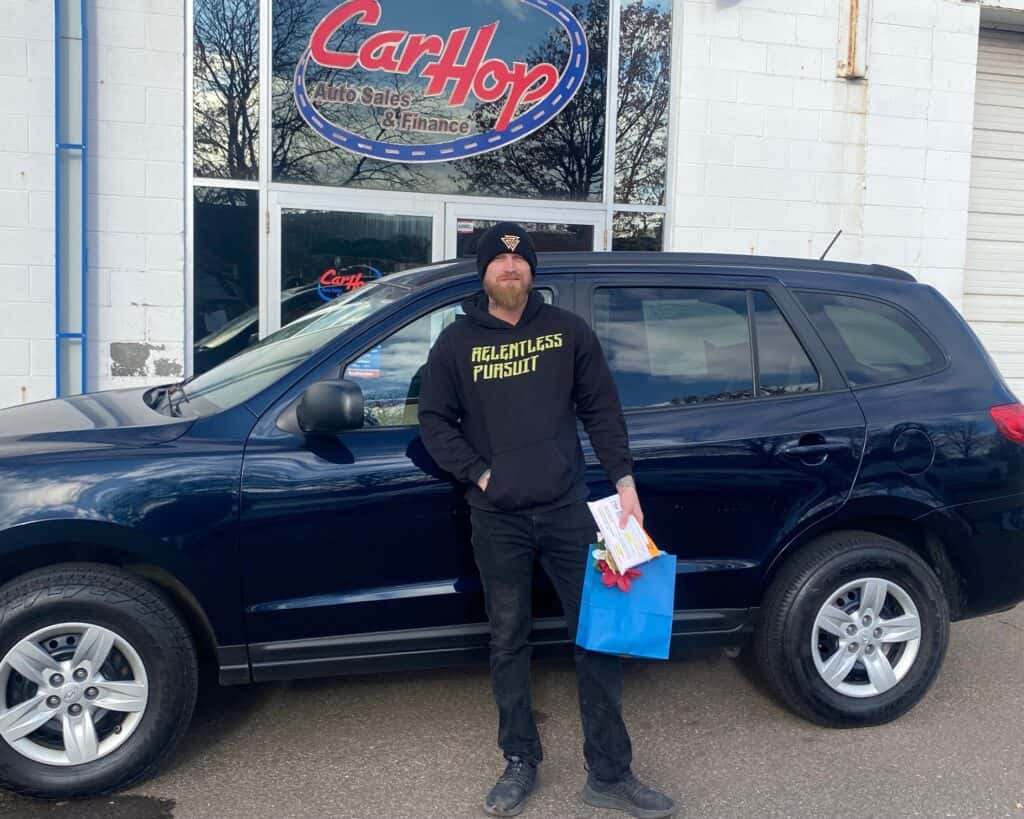 carhop customer with their new suv in blaine and carhop cares gift bag