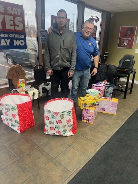 A grateful family at CarHop of Spokane receiving gifts, including Pampers, baby clothes, pajamas, and other essentials for their newborn.