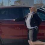 Excited customer posing joyfully next to a red used SUV, celebrating an easy and affordable car purchase experience