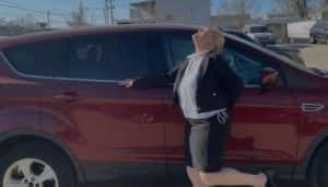 Excited customer posing joyfully next to a red used SUV, celebrating an easy and affordable car purchase experience
