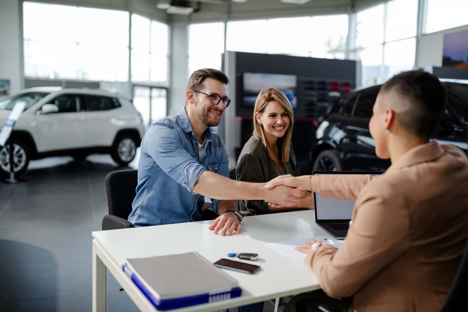man shaking hands with a sales person while his wife sits next to him