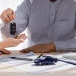 person handing keys to another person at a dealership