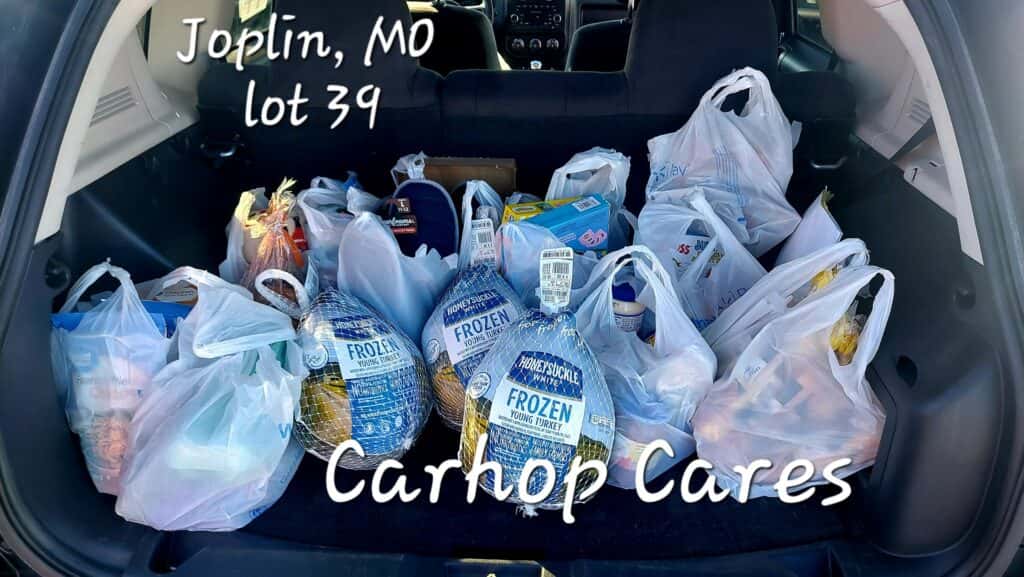 Customers of CarHop of Joplin smiling with their Thanksgiving baskets, including a turkey and other holiday meal staples.