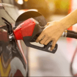 a hand holding a red gas pump filling up the gas tank of a black vehicle