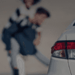 Close-up of silver used car taillight with smiling family in the background, symbolizing reliable used cars and happy customers