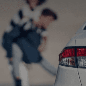 Close-up of silver used car taillight with smiling family in the background, symbolizing reliable used cars and happy customers