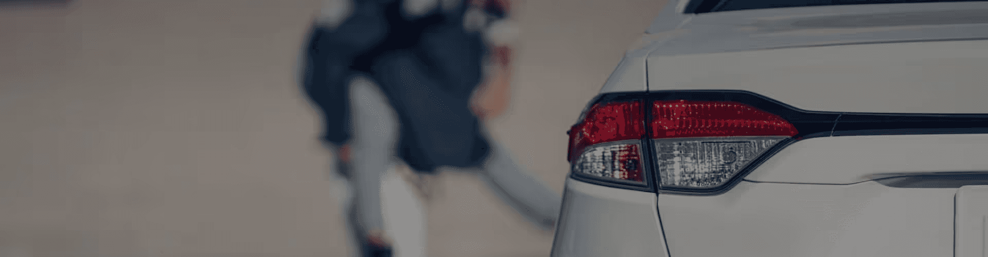 Close-up of silver used car taillight with smiling family in the background, symbolizing reliable used cars and happy customers