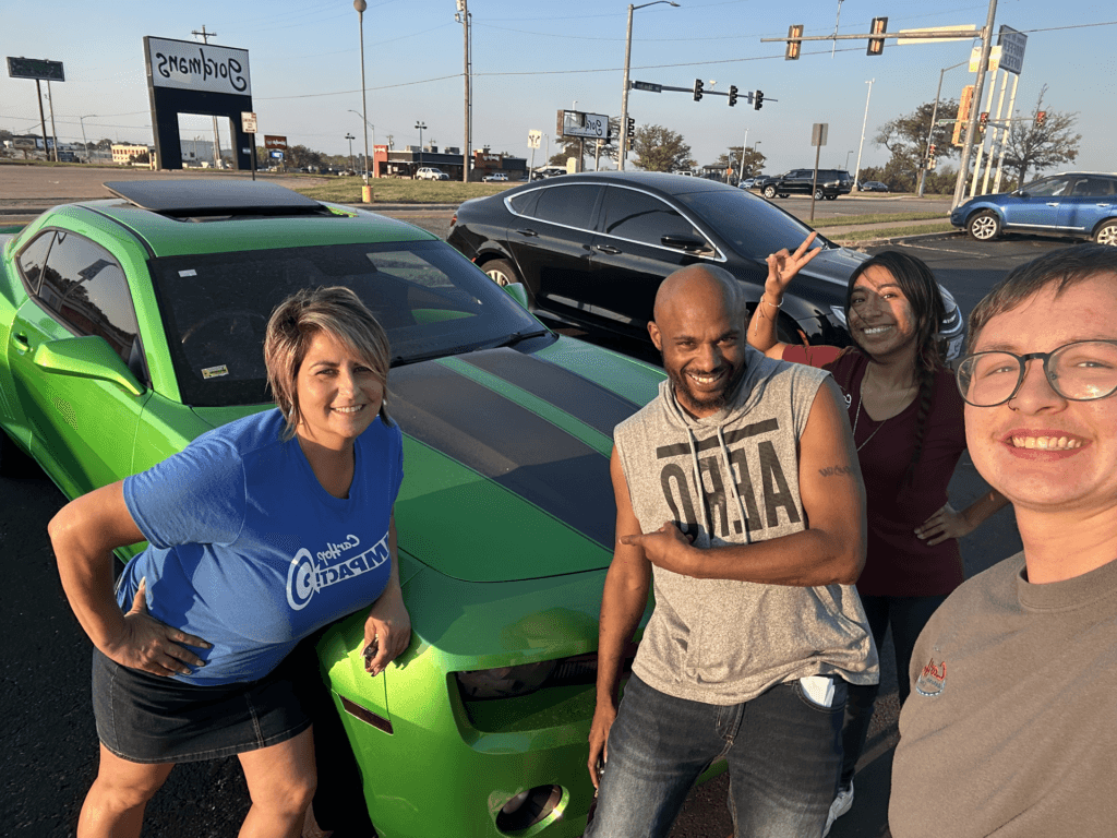 carhop of topeka customer smiling with the sales team infront of their new green camaro
