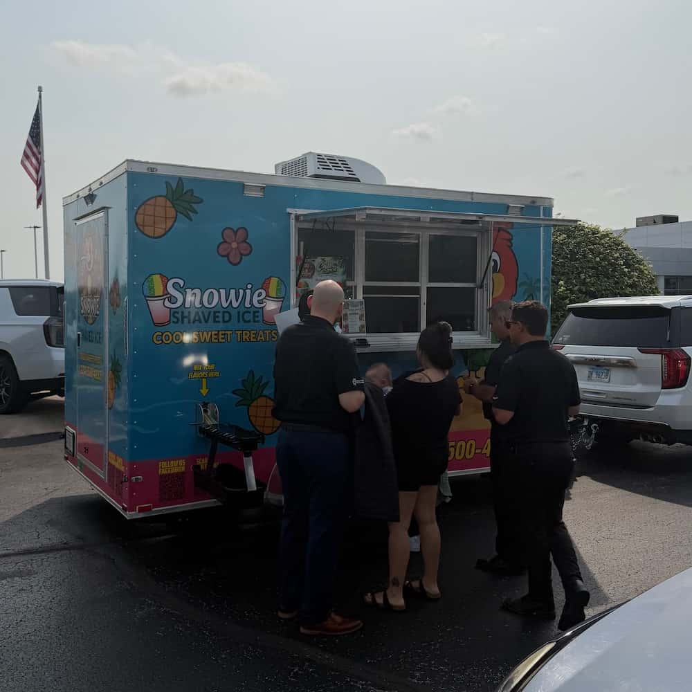 Snowie Ice serving refreshments to families during the Cars and Cuts event in McHenry