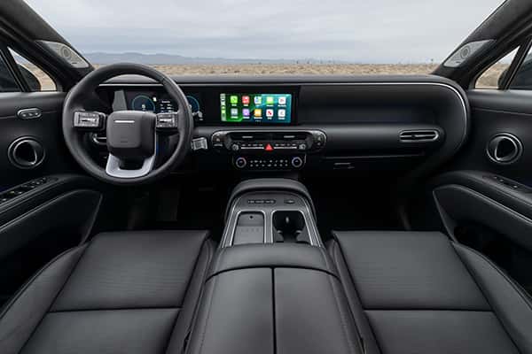 Interior of the 2026 Hyundai Palisade Hybrid Calligraphy model shown in black leather. Dashboard view showing large LCD infotainment screen, ample storage and upscale design. Get yours at Castle Hyundai in Downers Grove, IL.