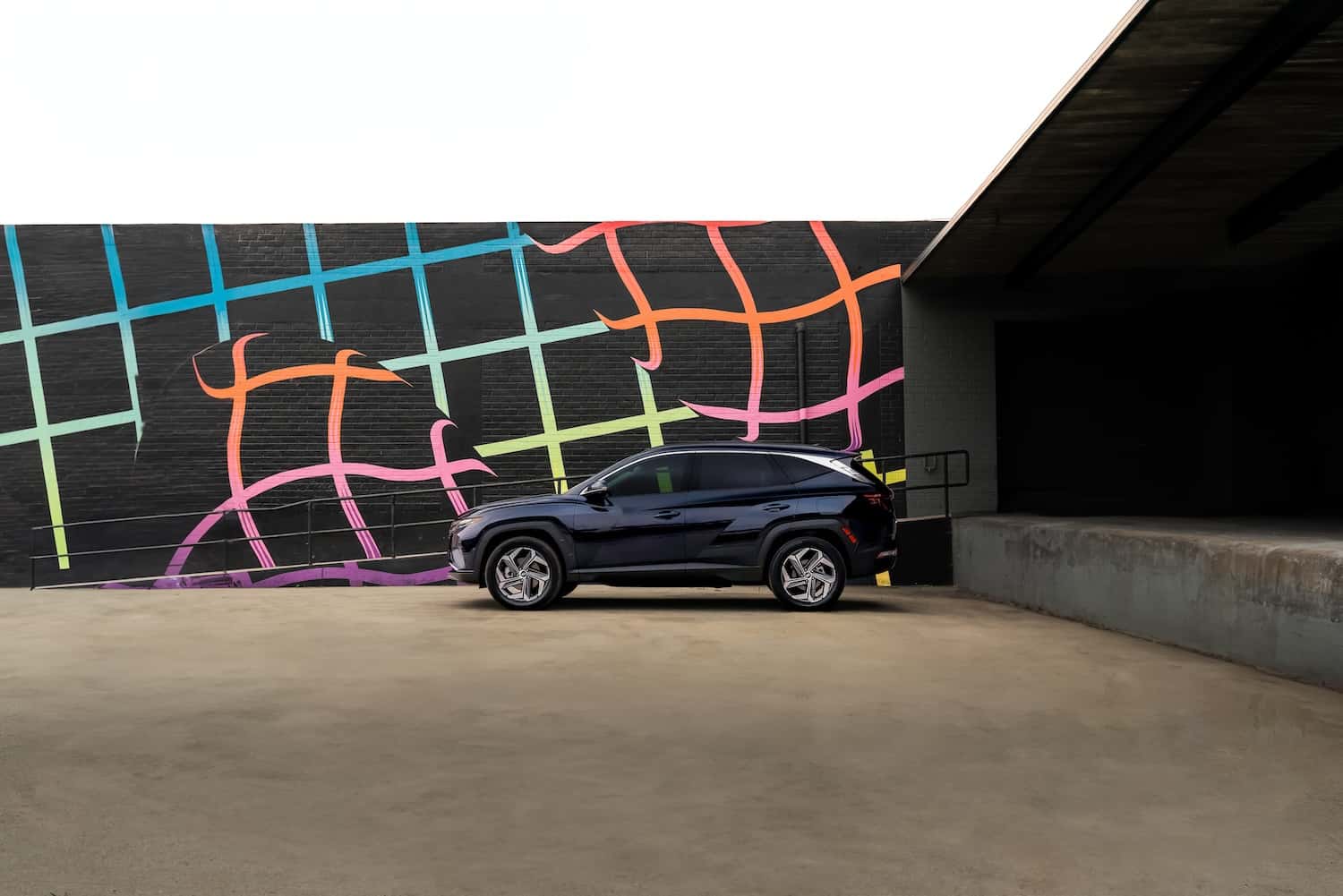 Hyundai Tucson Hybrid parked in front of a colorful neon grid wall