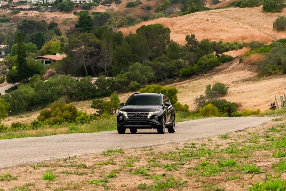 Hyundai Tucson Hybrid driving on a country road through rolling hills