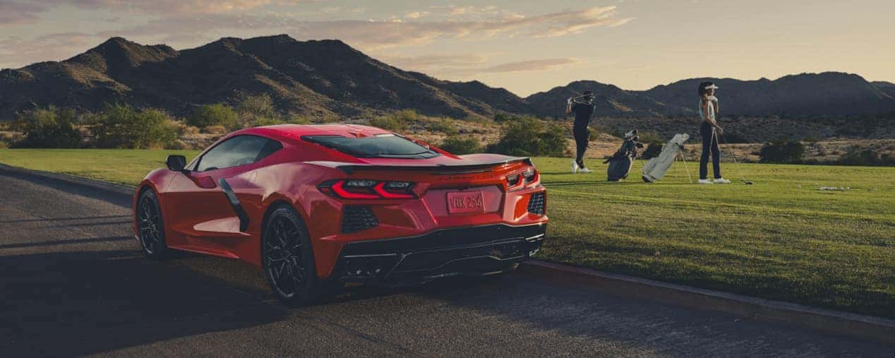 A red 2025 Chevrolet Corvette Stingray parked near a golf course with players in the background, showcasing its sleek, high-performance design. Available at Castle Rock Chevy.